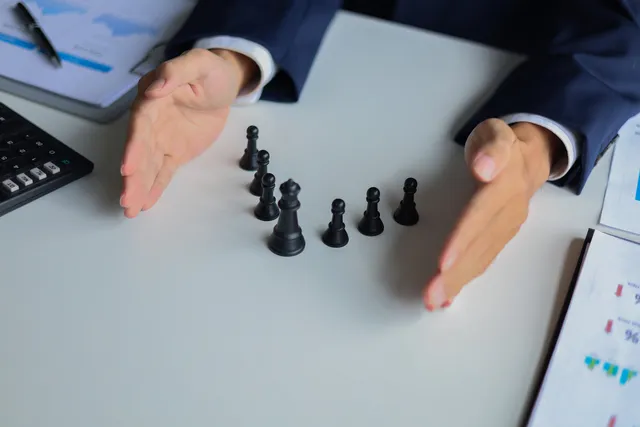 Businessman wearing suit, playing chess game. Business strategy, leadership, planning and management concept.